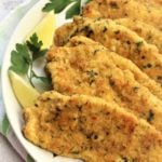 breaded chicken cutlets on plate with parsley and lemon wedges