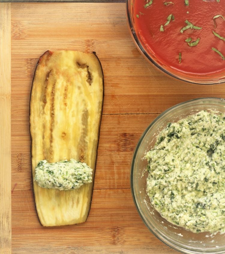 ricotta spinach filling on eggplant slice with bowl of sauce and bowl of spinach ricotta filling