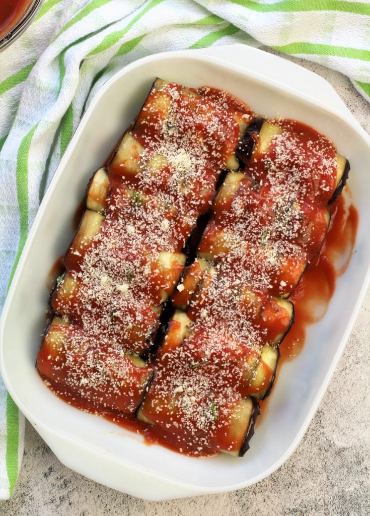 eggplant involtini in baking dish covered with sauce and grated cheese