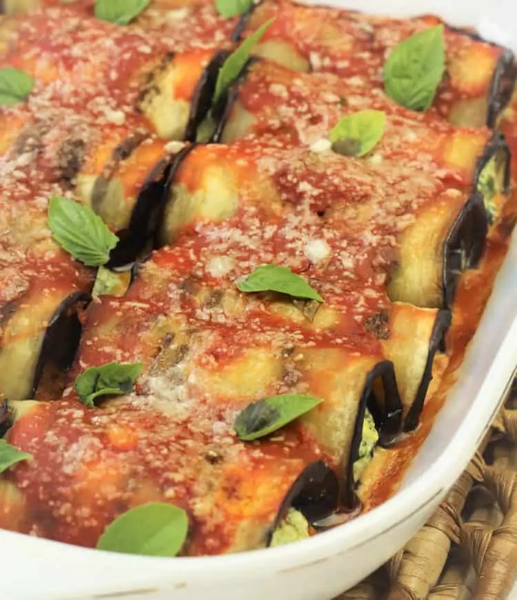 eggplant involtini covered with sauce and basil in baking dish