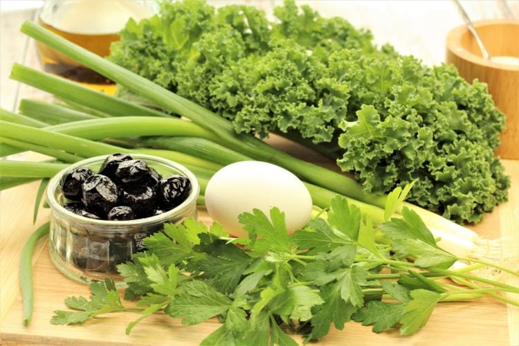 kale, green onions, parsley, egg and black olives on wood board