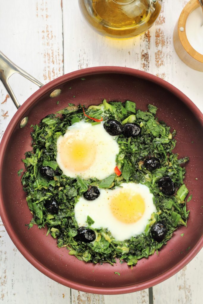 skillet with fried eggs with greens 
