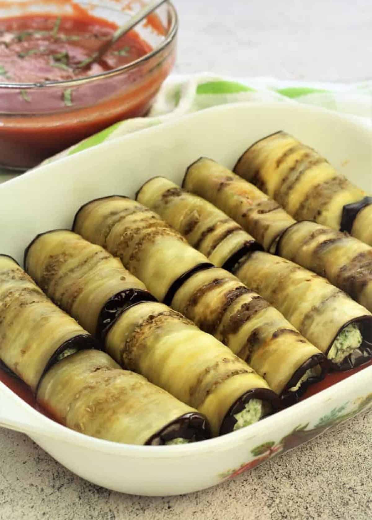 Casserole dish filled with rows of eggplant rolls.
