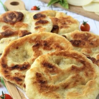 fried pizza dough rounds overlapped on wood board with cherry tomatoes around it