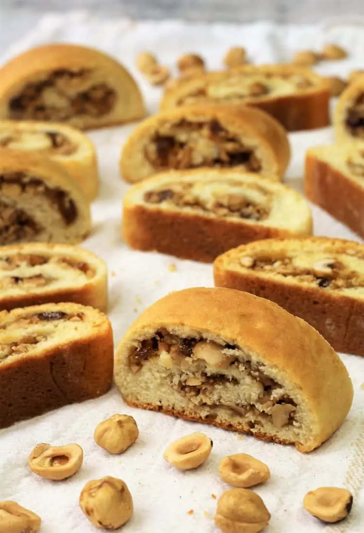 hazelnut and jam rolled cookies on white dish towel with halved hazelnuts