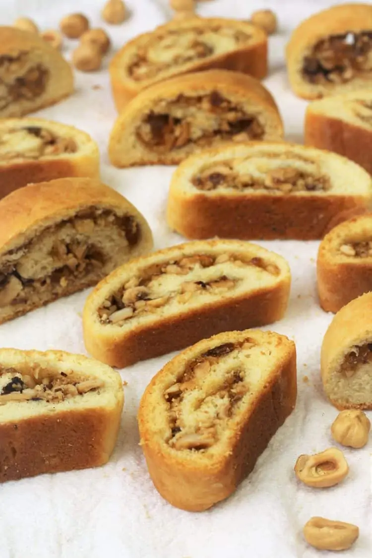 sliced biscotti filled with hazelnuts and jam on dish cloth with halved hazelnuts