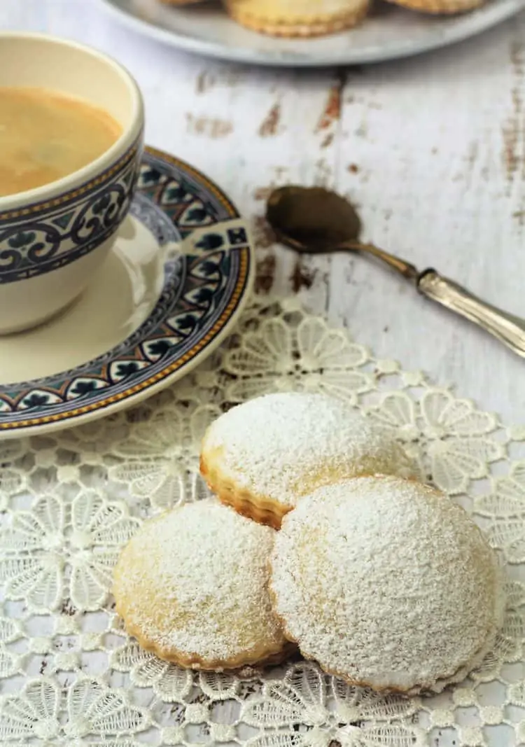 genovesi ericine cookies on lace doily next to coffee cup and spoon