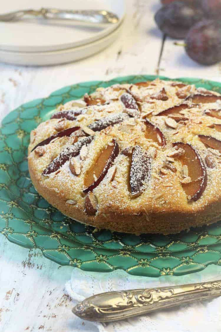 Plum Almond Cake Plum almond cake dusted with powdered sugar on green plate.