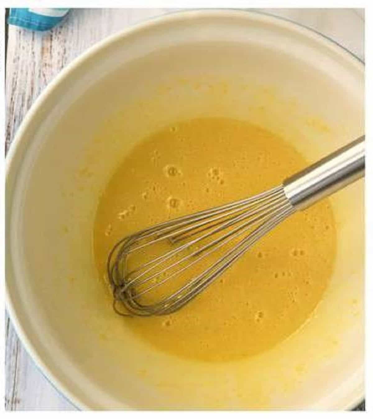 Eggs and sugar whisked in large bowl for plum almond cake.