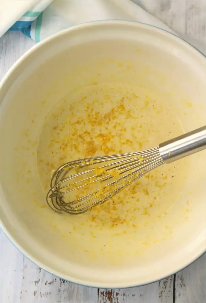 Lemon zest added to whisked eggs and sugar in bowl.