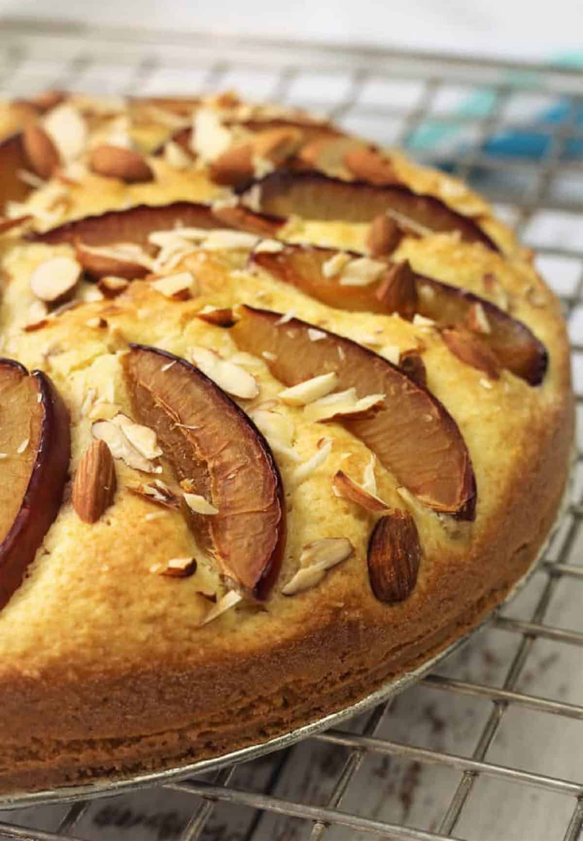 Plum almond cake on wire rack.