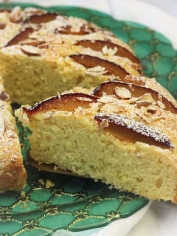 Italian plum almond cake wedge cut from whole cake on green plate.