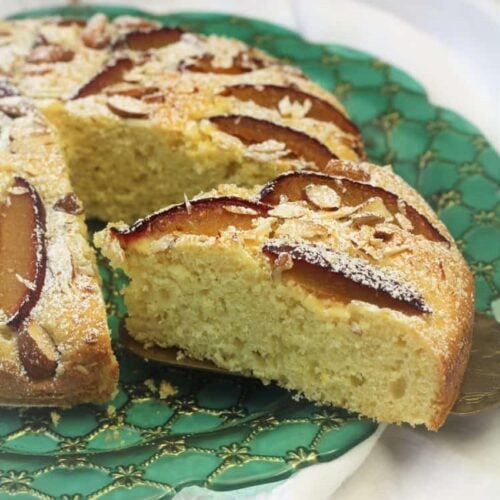 Italian plum almond cake wedge cut from whole cake on green plate.