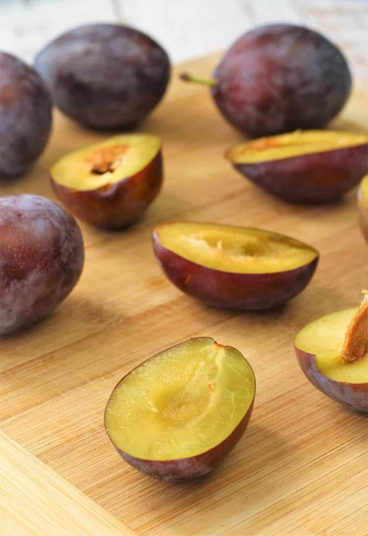 Plum Almond Cake Italian plums halved on wood board for plum cake.