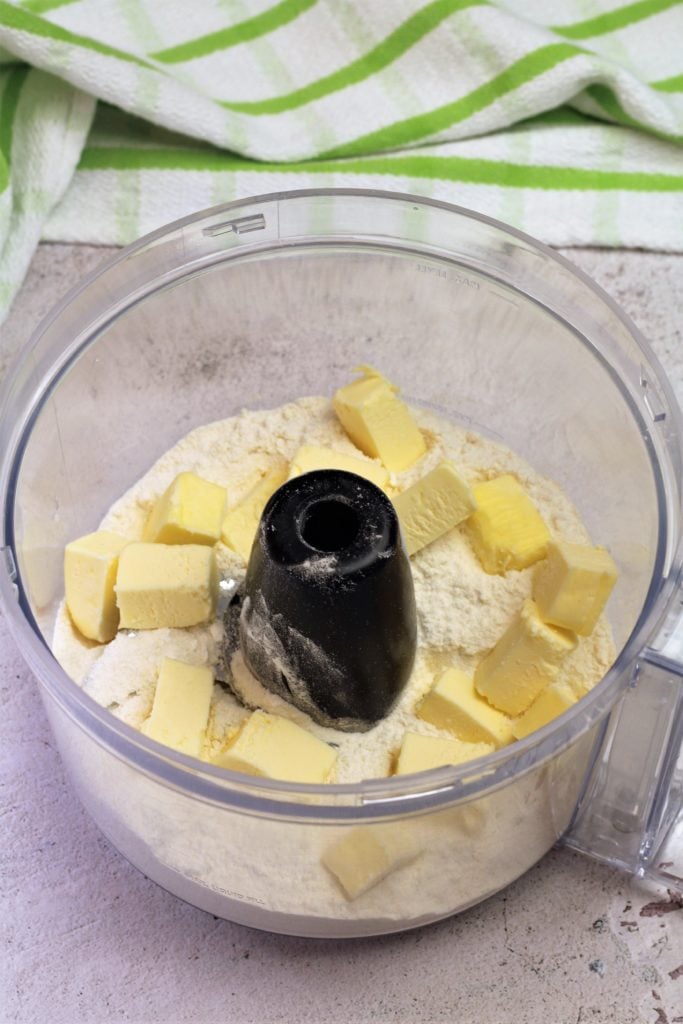 cubed butter on flour mixture in food processor bowl