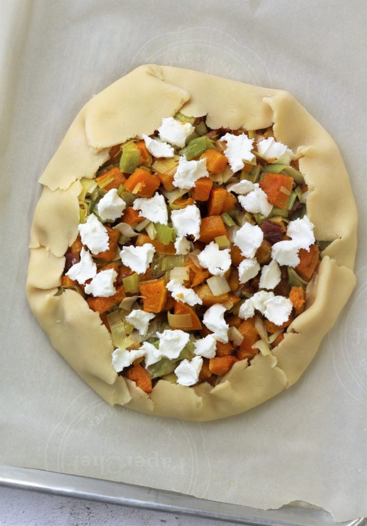 assembled crostata filled with butternut squash, leeks and goat cheese on baking sheet 