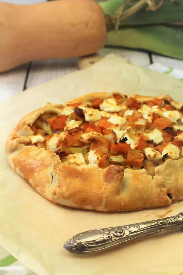 crostata filled with butternut squash, leeks and goat cheese on parchment paper with serving spatula