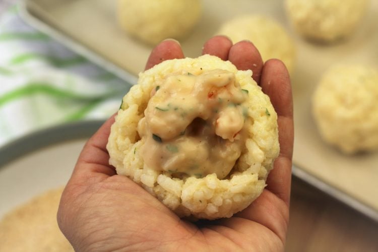 hand shown with rice ball with seafood mixture being shaped 