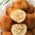 halved seafood filled arancini on pile of arancini rice balls