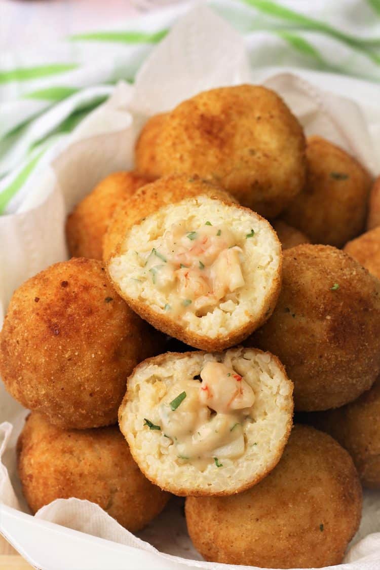 halved seafood filled arancini on a pile of plated arancini rice balls