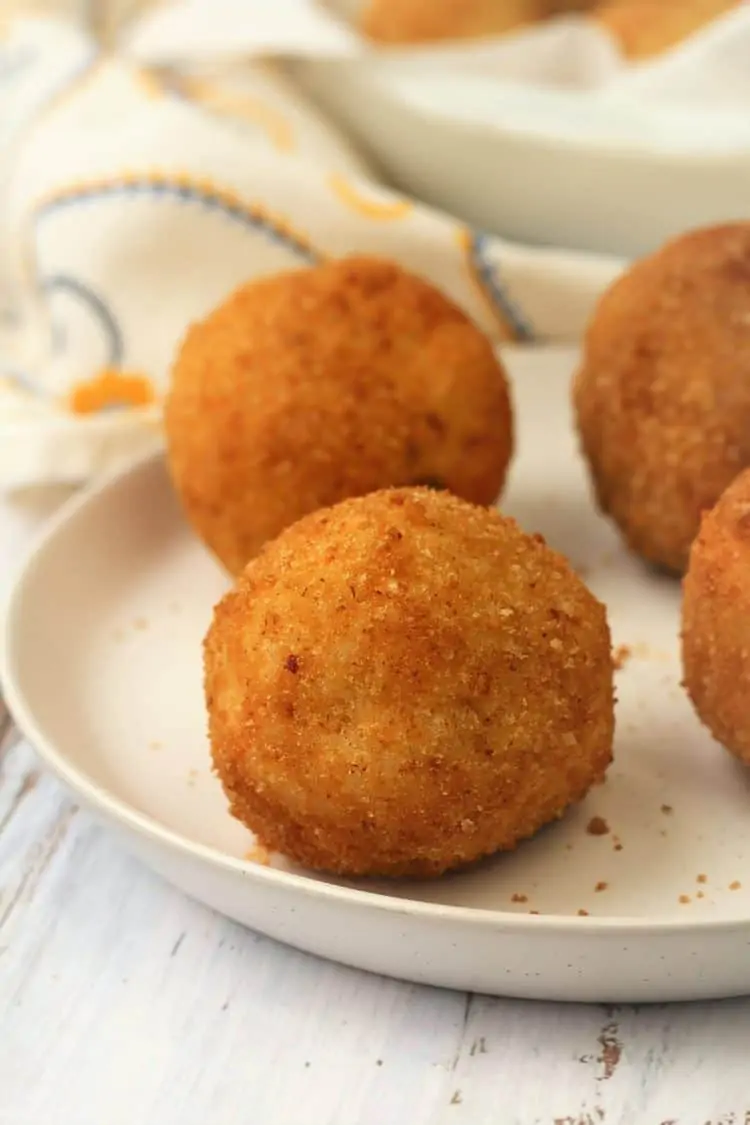 rice balls, or arancini, on white round plate