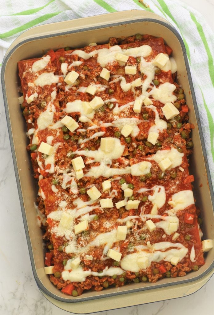 overhead view of lasagna topped with bechamel, mozzarella and grated cheese