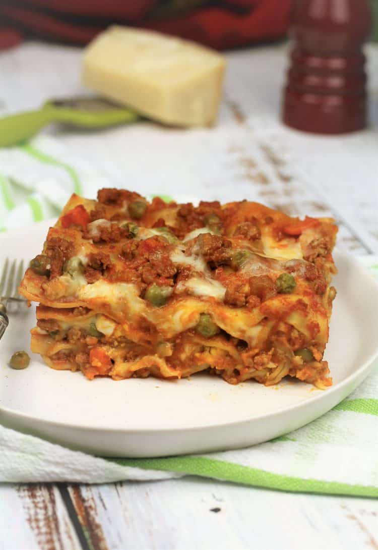 slice of Sicilian lasagna on white plate with fork 