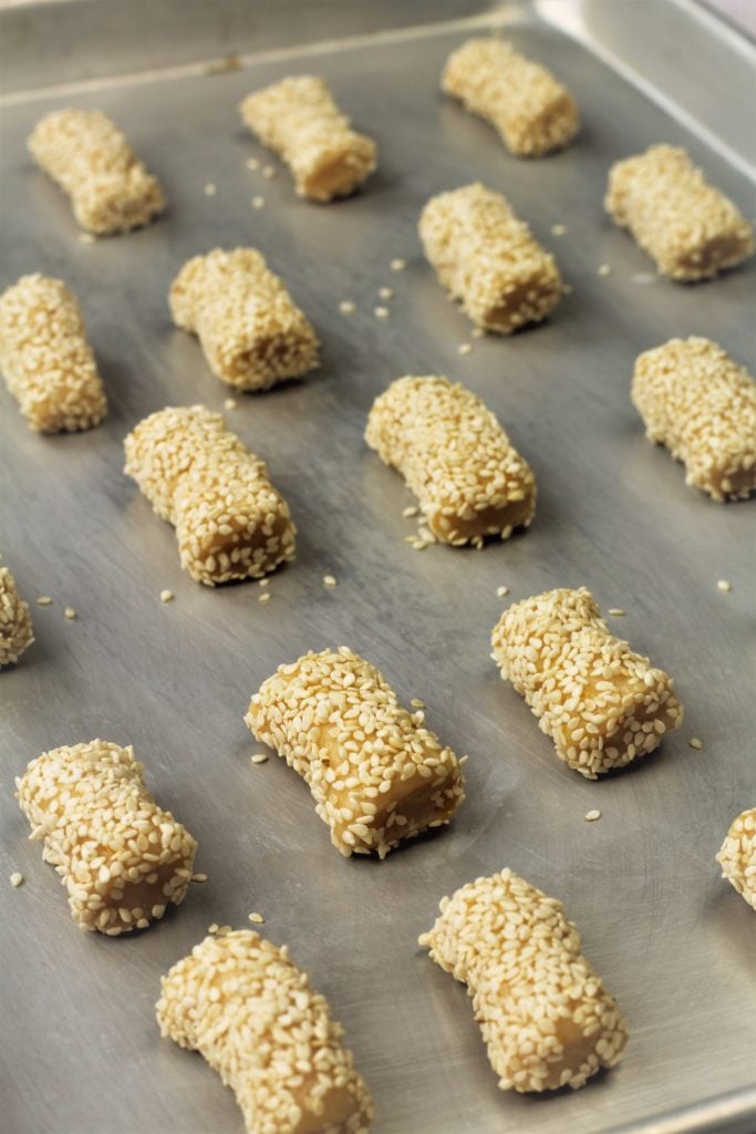 cookies covered in sesame seeds on baking sheet