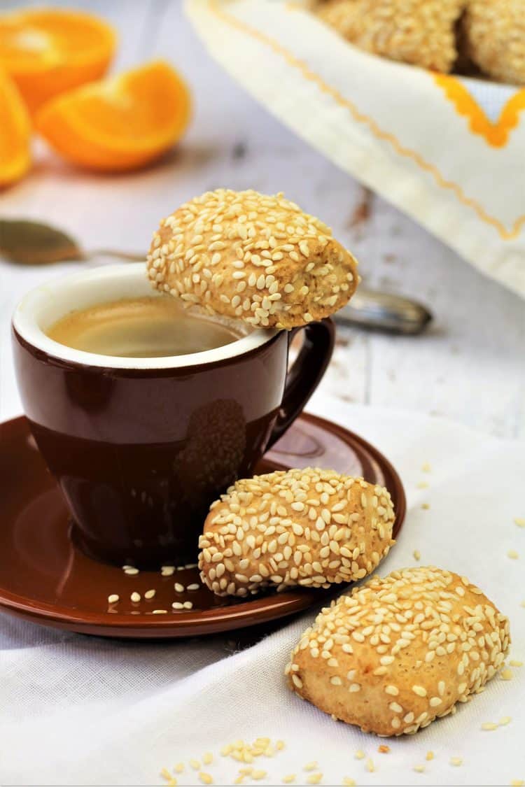 brown espresso cup with saucer and 3 sesame seed cookies resting alongside 