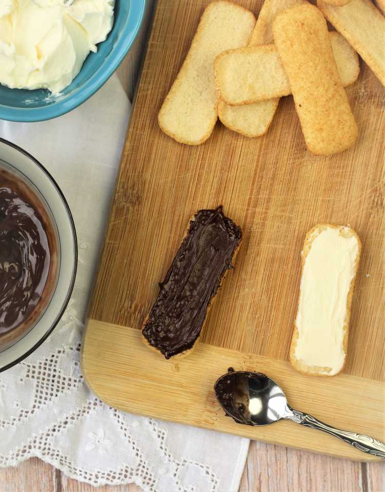 pavesini cookie spread with Nutella and mascarpone cheese on wood board with spoon and more cookies