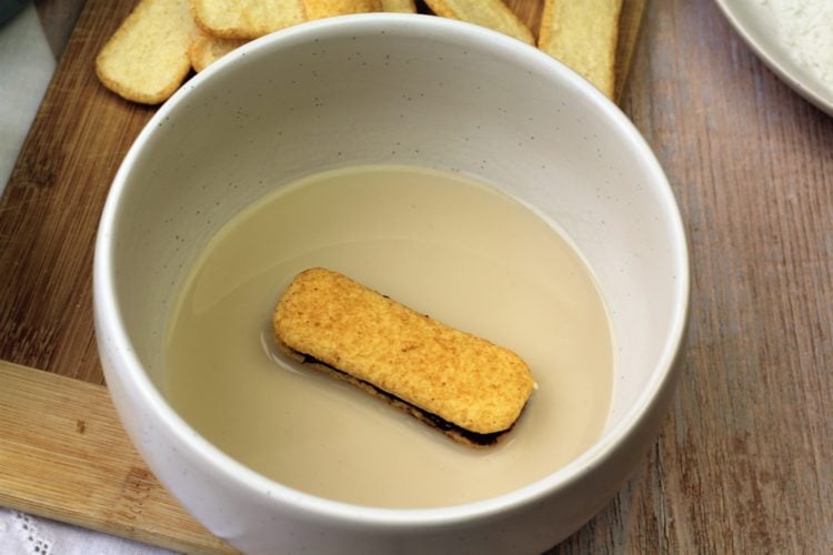 Pavesini cookie sandwich dredged in bowl with milk