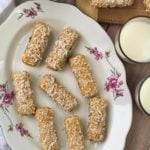 lady finger sandwiches dipped in shredded coconut on serving platter with glasses of milk