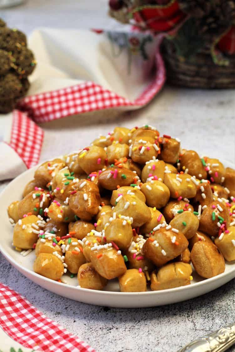 pignolata honey balls topped with candy sprinkles on white plate