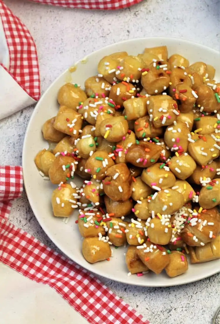 pignolata balls coated in honey and candy sprinkles on round plate