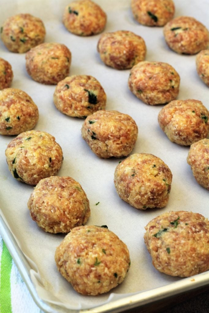 raw meatballs on parchment paper covered baking sheet
