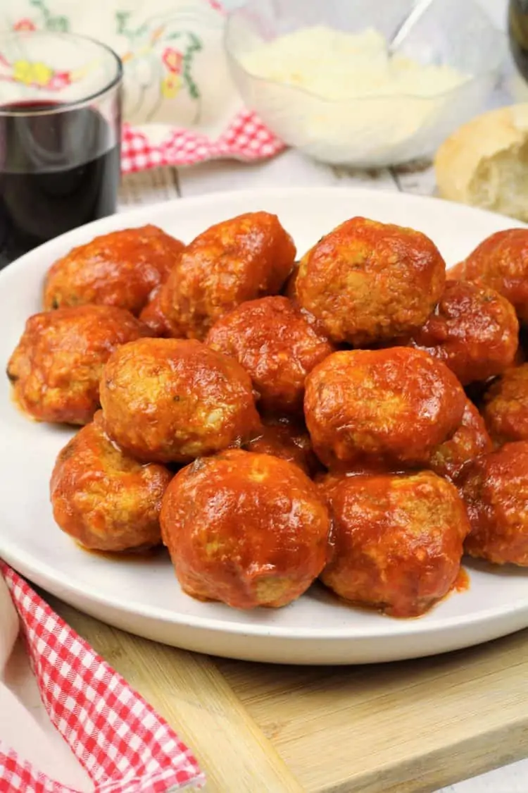 meatballs covered in tomato sauce piled onto white round plate 