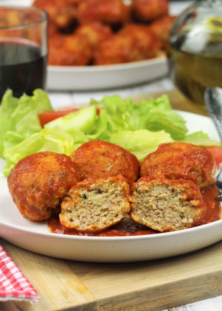 Traditional Sicilian Meatballs (prupetti) halved meatball served on white round plate with other meatballs and salad