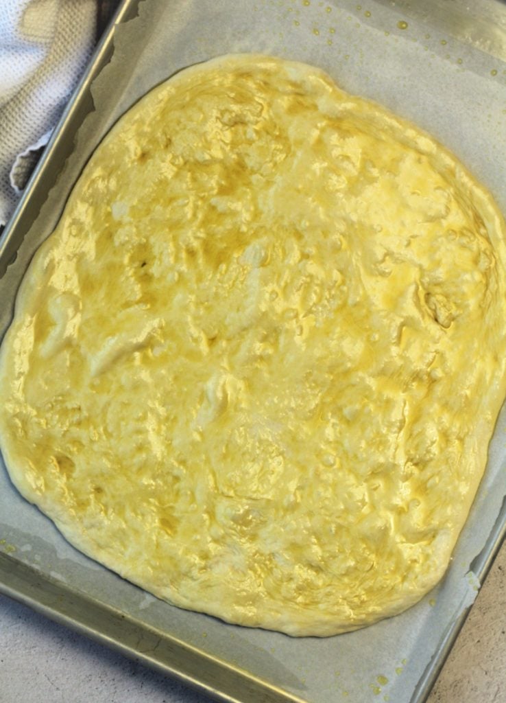 flattened pizza dough burshed with oliveoil