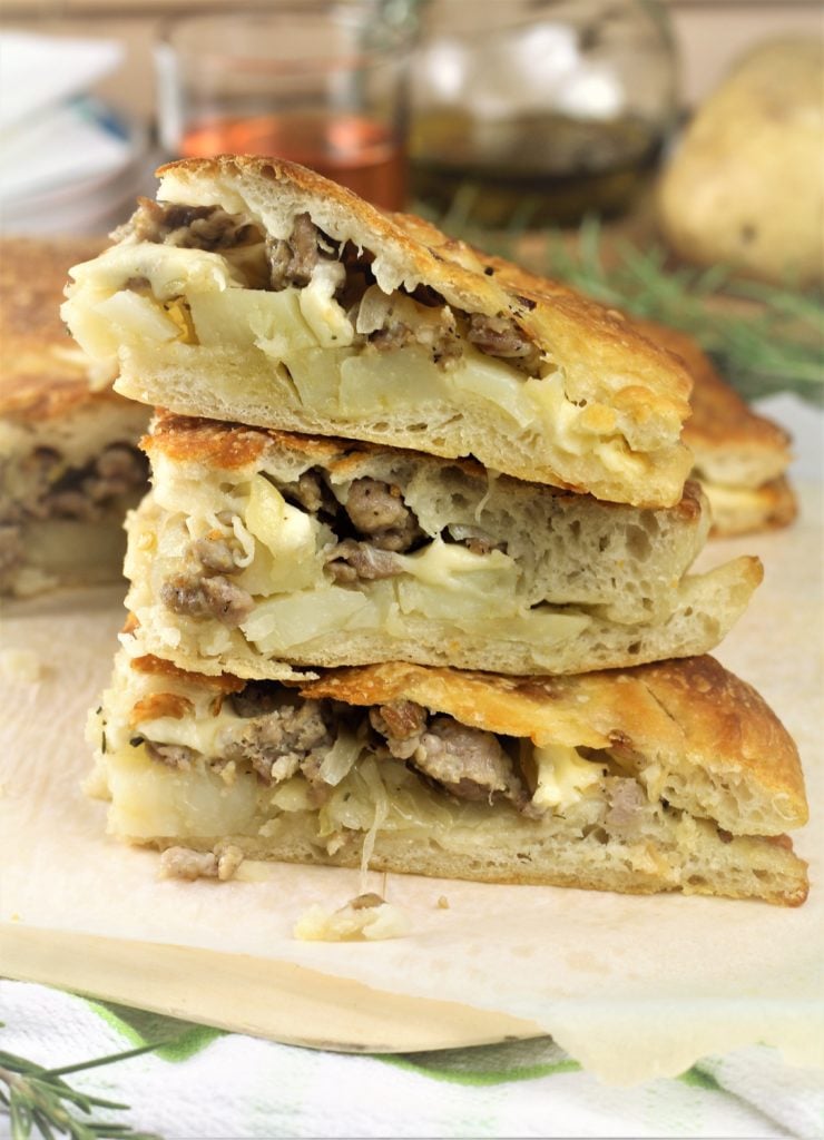 stacked slices of scacciata with potato and sausage filling