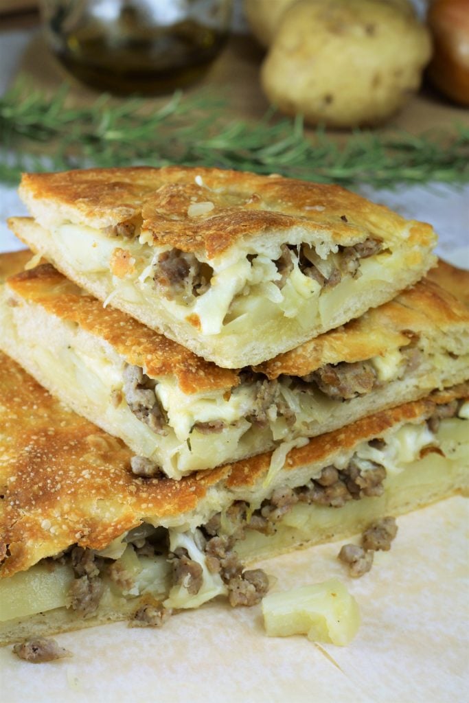 stacked wedges of scacciata with sausage and potato filling