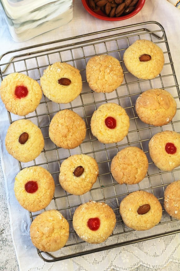 orange juice cookies with cherries and almonds in center on wire rack