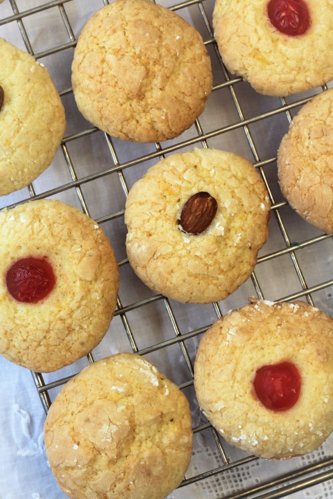 orange juice cookies with almonds and maraschino cherries on cooling rack