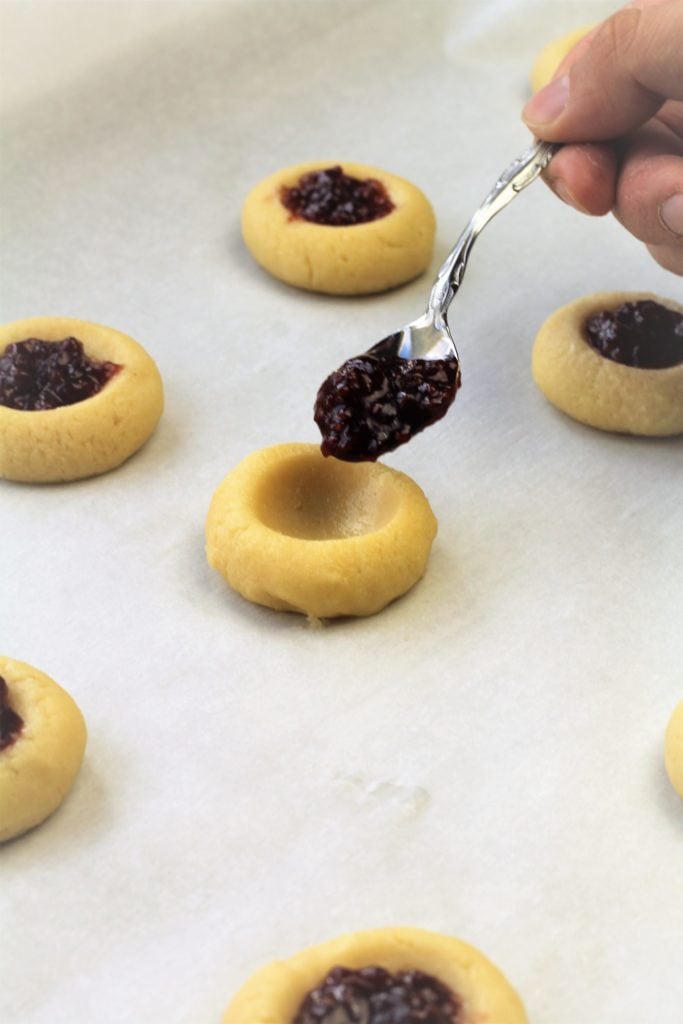 filling thumbprint cookies with a spoonful of jam