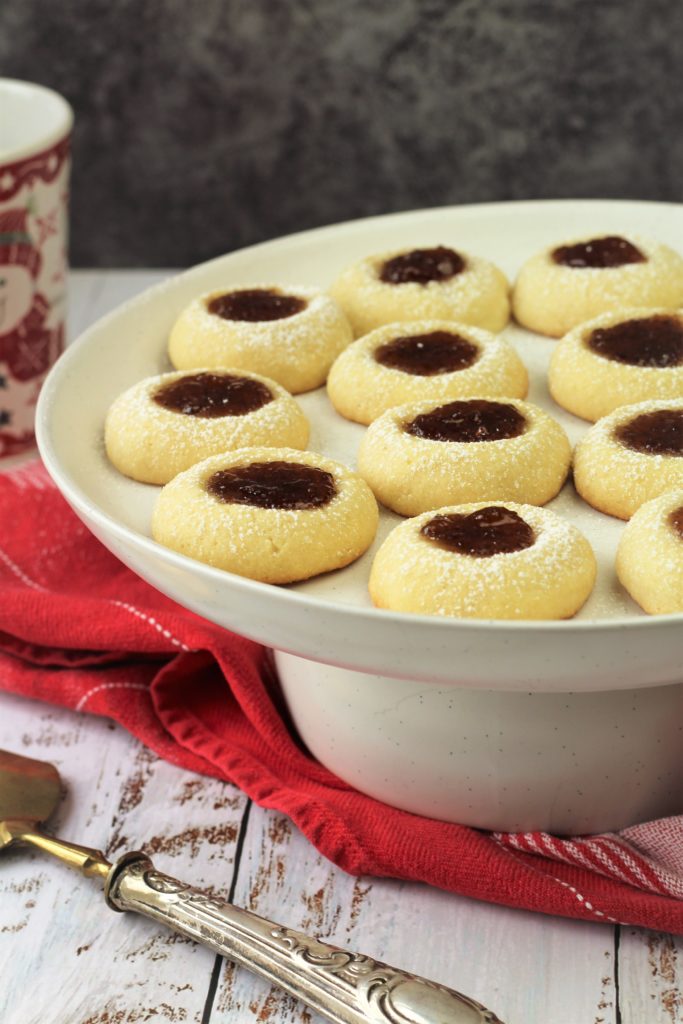 jam filled thumbprint shortbread cookies on white cake stand 