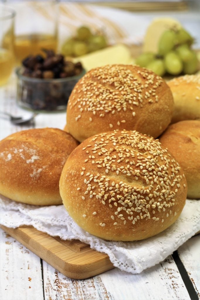 semolina rolls topped with sesame seeds on wood board