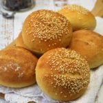 semolina rolls topped with sesame seeds on wood board