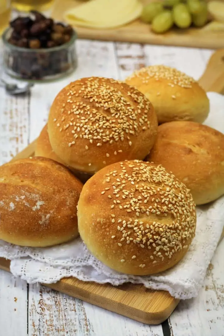 semolina rolls topped with sesame seeds on wood board