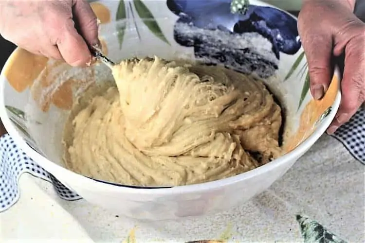 hands mixing batter with fork in large bowl
