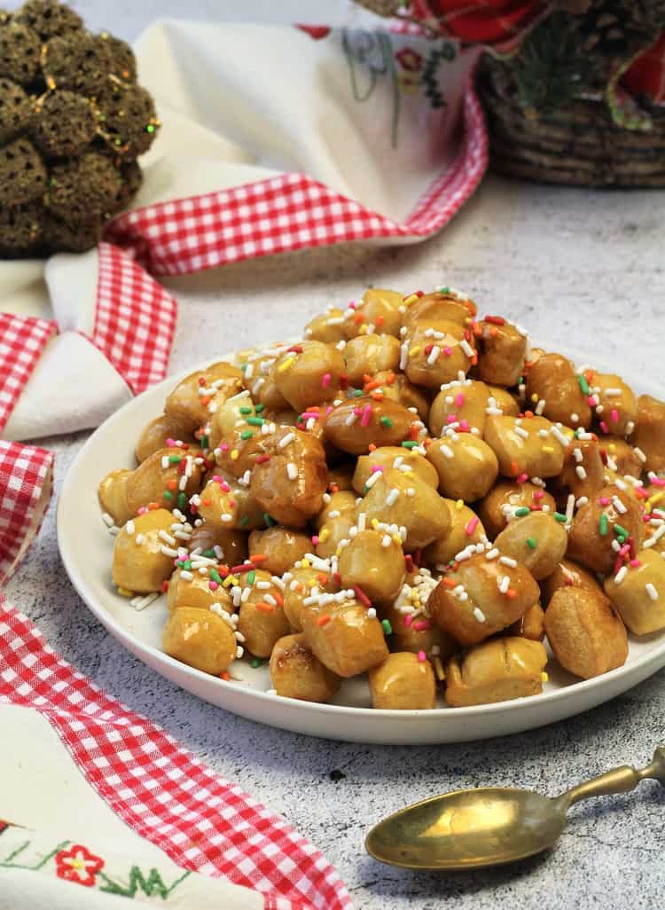 pignolata honey balls coated in candy sprinkles mounded on plate