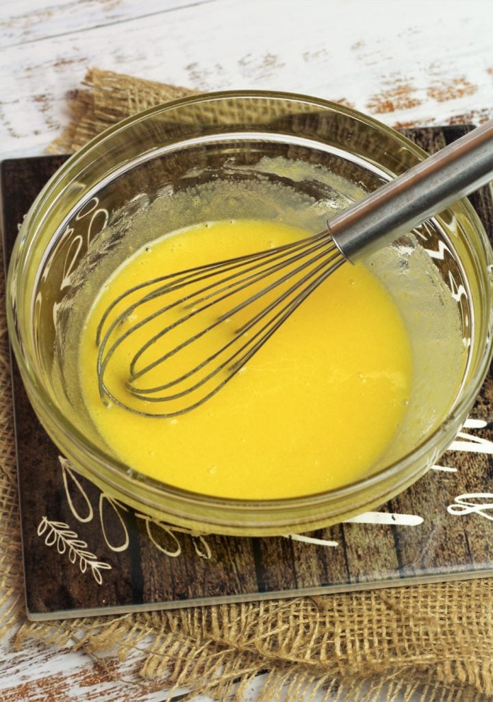 Eggs whisked with sugar in bowl.